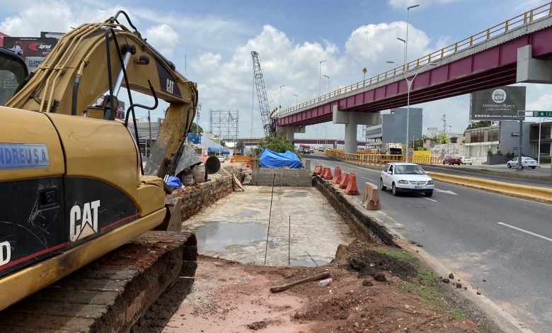 Se le añade y sobrepone otro carril elevado para corregir el Distribuidor Vial Universidad, y sube el costo de la obra